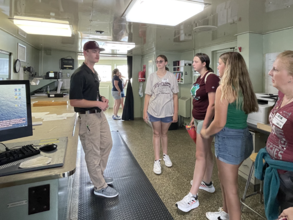 Student giving tour of ship to a group of people.