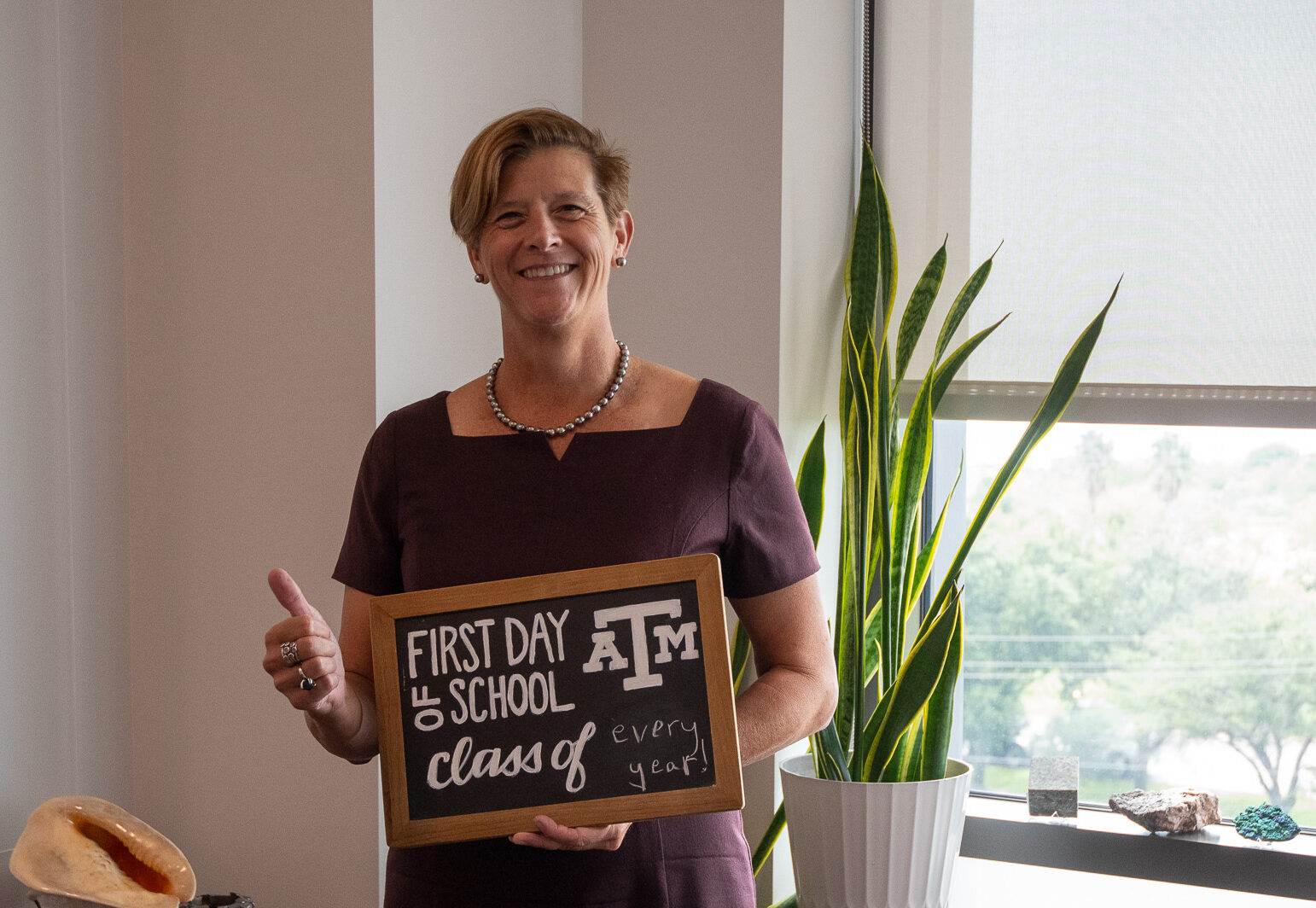 Debbie Thomas holding a sign that says "first day of school"