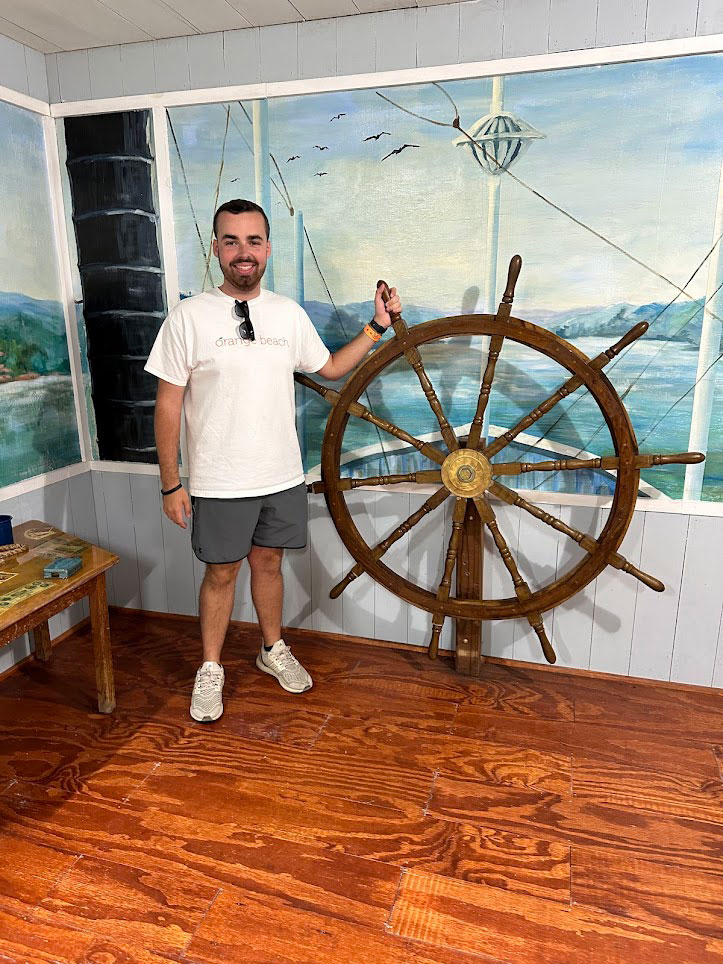 Hunter Newton '25 posing next to a ship's wheel.