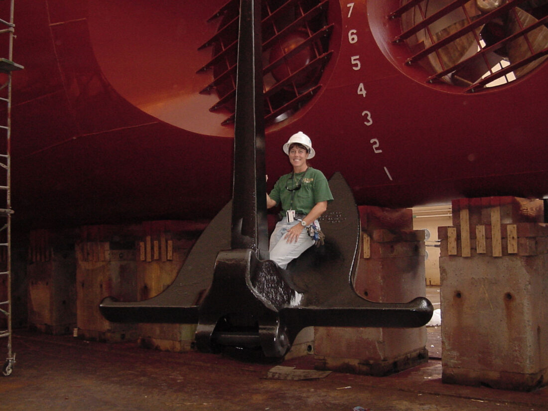 Kristin Mangold ’87 seated on a ship’s anchor.