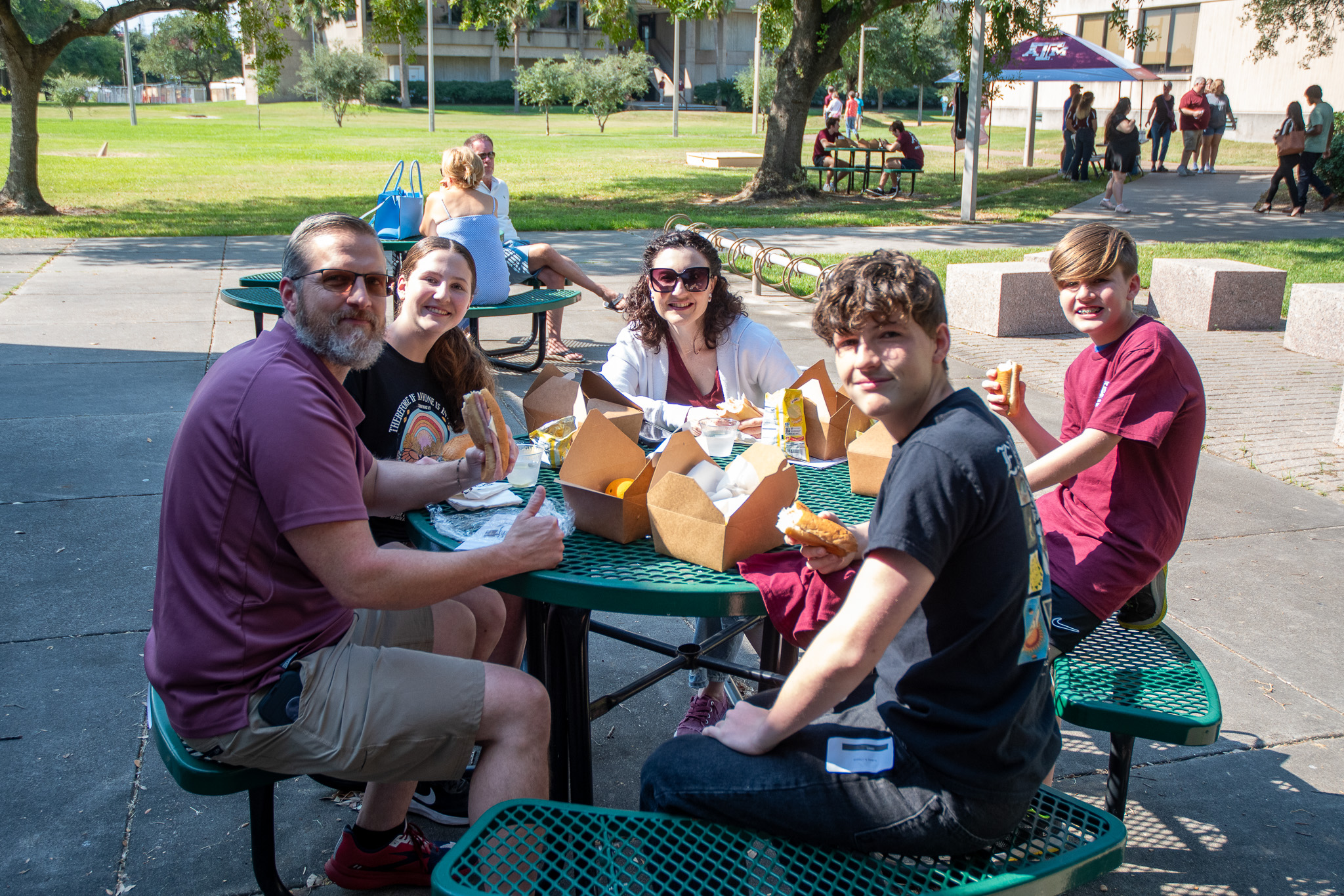 Visitors to Aggieland Saturday by the Sea sitting at a picnic table outside of the library