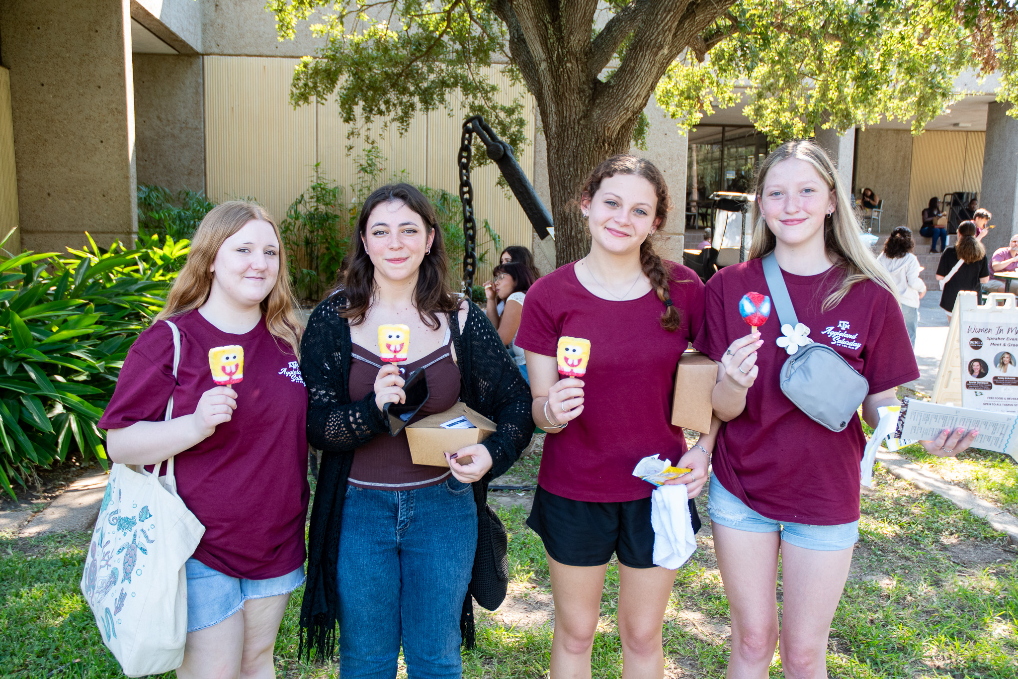 Visitors to Aggieland Saturday by the Sea holding ice cream treats in front of the library