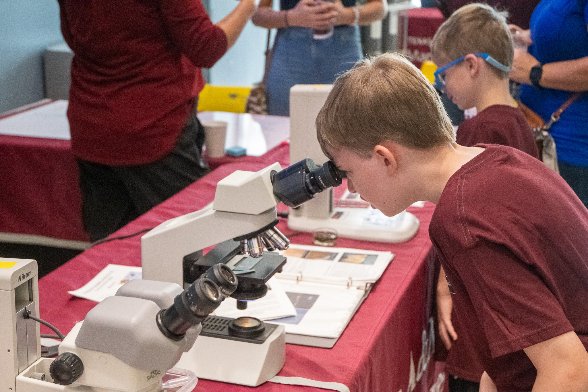 Visitor to Aggieland Saturday by the Sea looking through a microscope