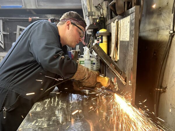 Lance Johnson using a grinder working on the welding work bench