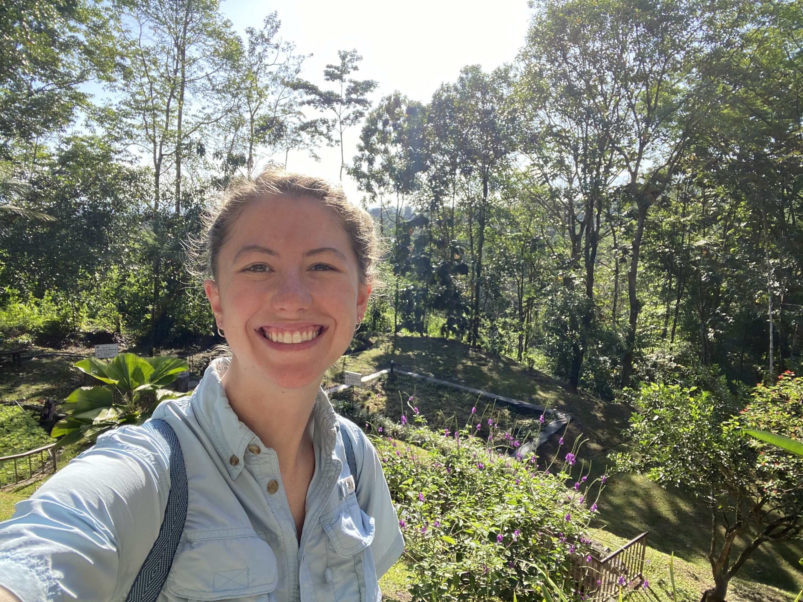 Tara Donnelly stands in the foreground with a rainforest in the background