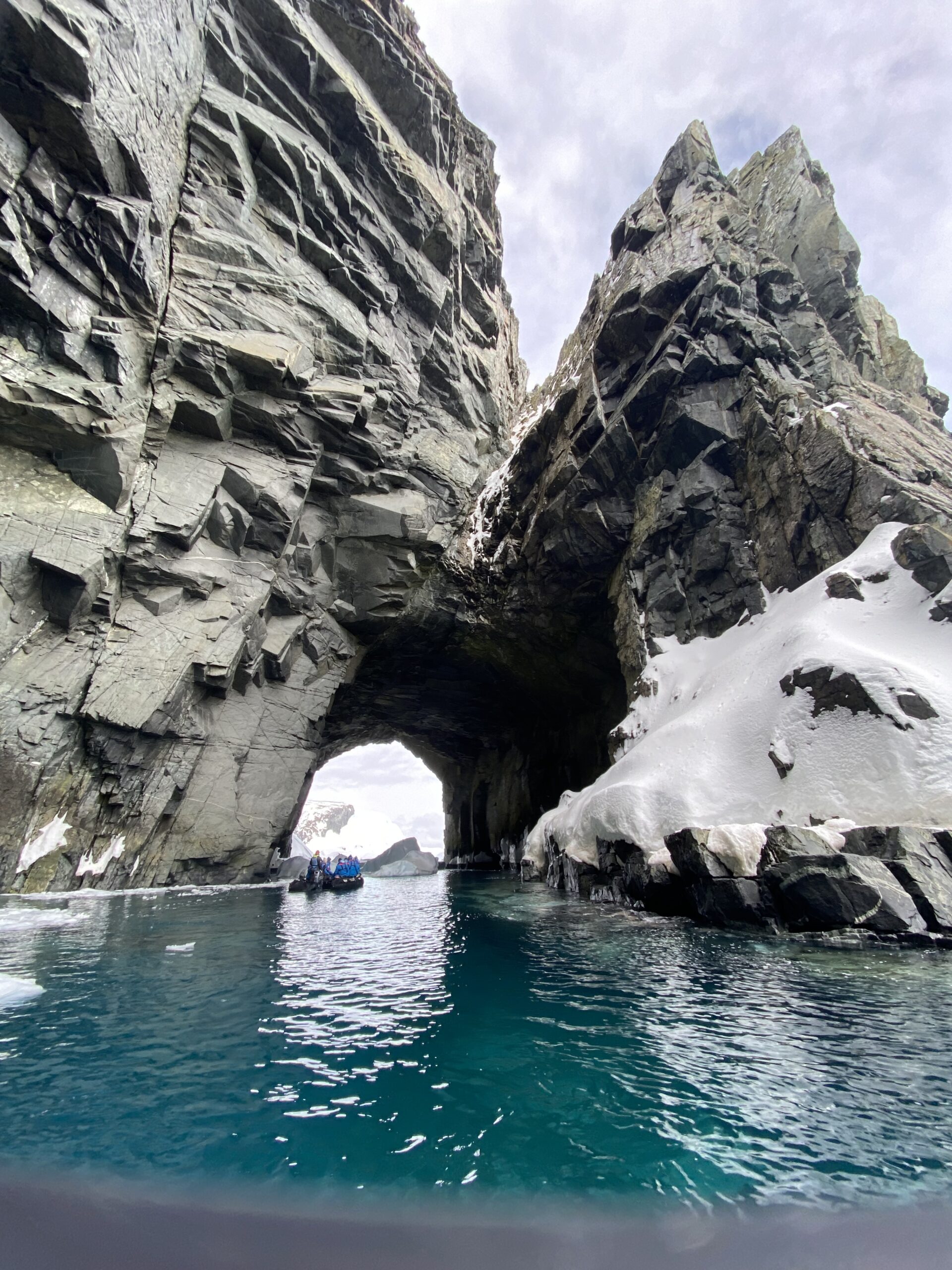 A large rock formation above teal water