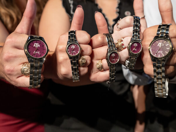 Five students display their Buck Weirus watches with their hands in a "thumbs up" position