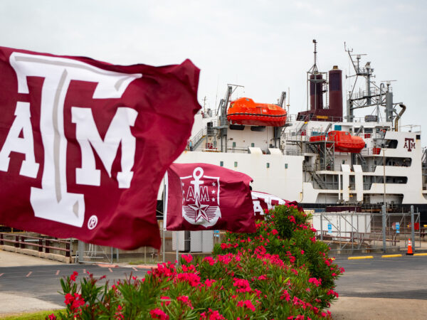 Docked TS Kennedy behind Texas A&M flags and campus landscaping