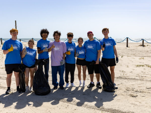 Students standing on the beach after picking up trash for The Big Event